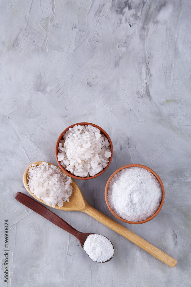 Conceptual composition of salt and pepper on spoons and bowls over light background, top view, close-up Conceptual composition of salt and pepper on spoons and bowls over light background, top view, close-up