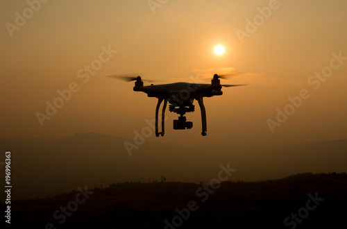 Drone silhouette flying in sunset landscape. drone quadcopter with digital camera at sunset ready to fly.