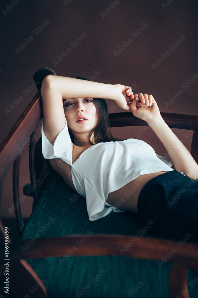 Fototapeta premium Beautiful thoughtful woman relaxing on sofa, hands bent behind head