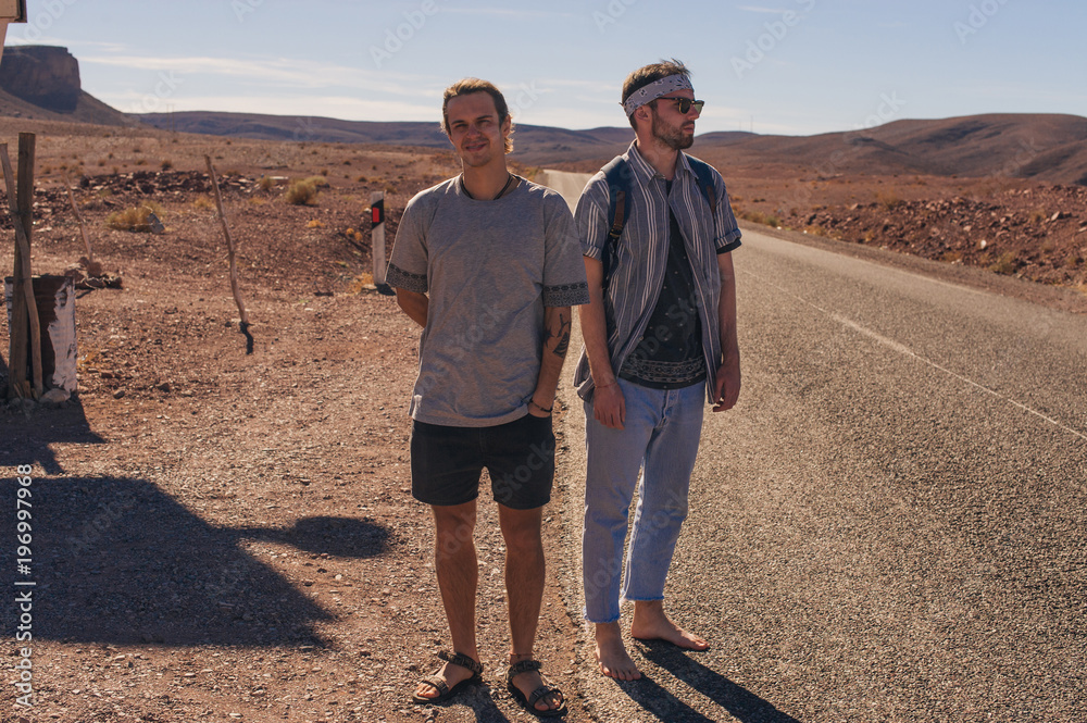 Two friends of tourists on the road in the desert Two friends of tourists on the road in the desert