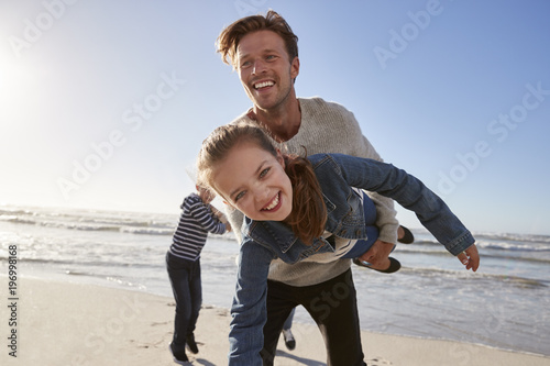 Father With Children Having Fun On Winter Beach Together