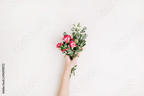 Woman hand hold rose flowers and eucalyptus bouquet on white background. Flat lay, top view spring blog hero header background.