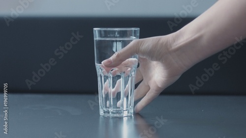 woman's hand picking a glass of water closeup with funny nail design