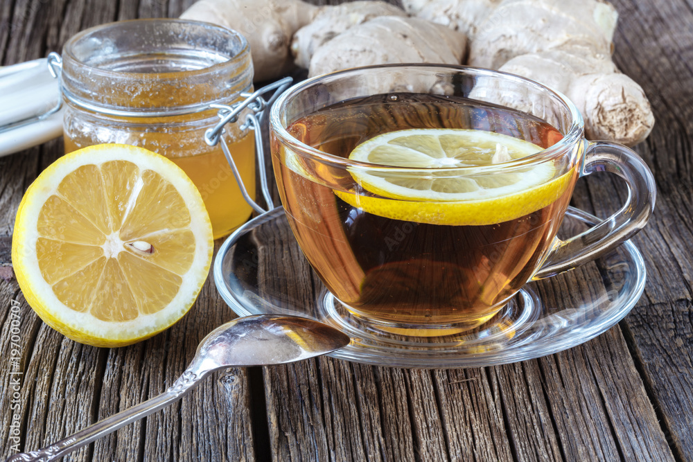 detail of cup of ginger tea with lemon and fresh ginger on wooden cutting board detail of cup of ginger tea with lemon and fresh ginger on wooden cutting board