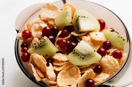 delicious crispy cornflakes with kiwi and berries in bowl over white background, healthy breakfast
