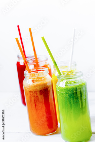 Fresh detox juices glass in row bottles on white background