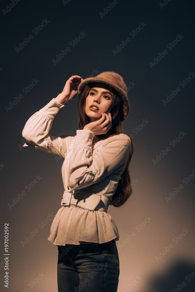 portrait of beautiful young woman in stylish clothing and hat posing on dark background portrait of beautiful young woman in stylish clothing and hat posing on dark background