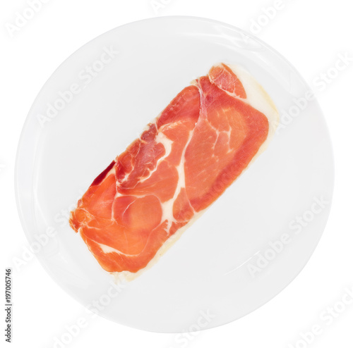 Single slice of raw prosciutto crudo or jamon on white plate isolated