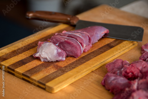 Man is cutting beef on an old board photo