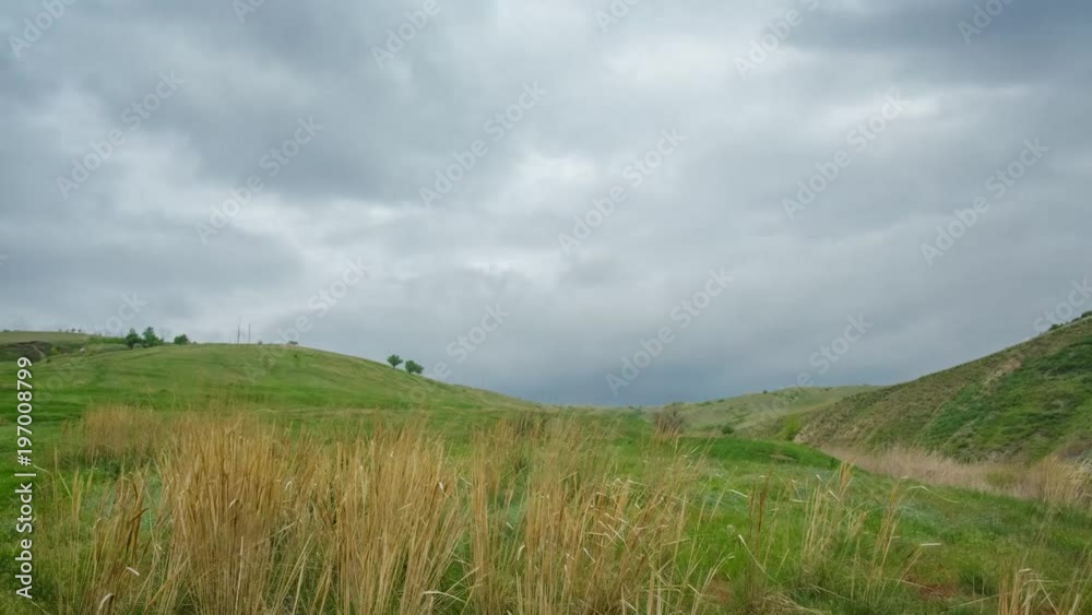 4K Timelaps Clouds among the hills quickly flying. A thunderstorm front looms in the summer. In the front, dry grass sways quickly 4K Timelaps Clouds among the hills quickly flying. A thunderstorm front looms in the summer. In the front, dry grass sways quickly
