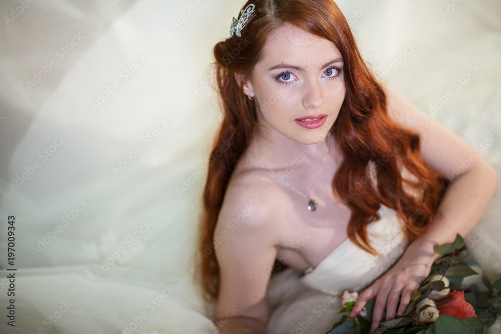 the bride with a bouquet of flowers leaning elbows on the bed and gently smiling looks into the camera. soft focus the bride with a bouquet of flowers leaning elbows on the bed and gently smiling looks into the camera. soft focus