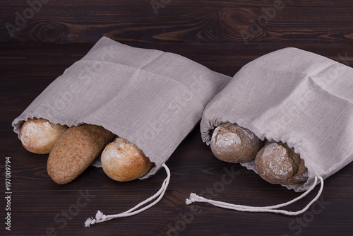 Homemade bread in a natural linen bag for storage on wooden background