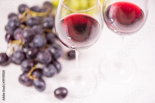 Fresh grape and red wine on the white table with two glasses, selective focus