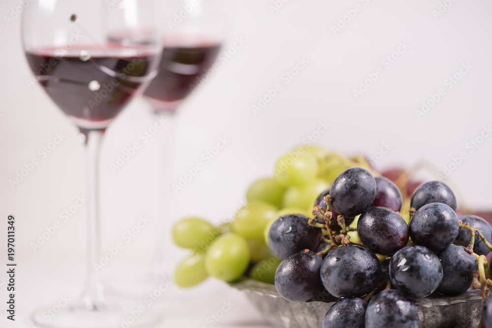 Fresh grape and red wine on the white table with two glasses, selective focus