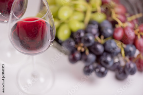 Fresh grape and red wine on the white table with two glasses, selective focus