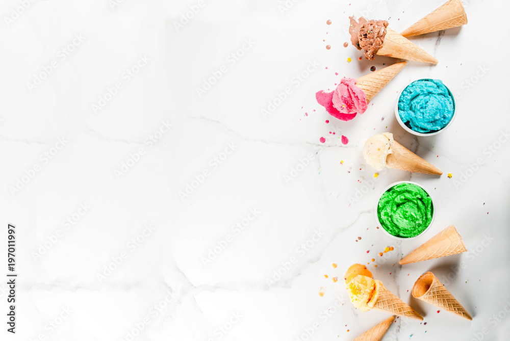 Different homemade melting ice cream in bowls and waffle ice cream cones, white vanilla, orange, pink berry, green, blue, chocolate white marble background  copy space top view