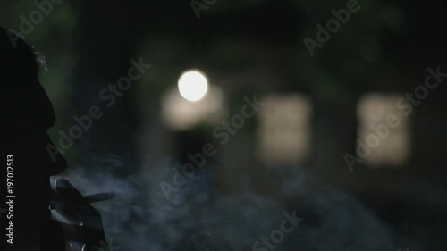 Man smoking cigarettes in front of a scary house