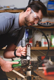 young man in protective goggles holding angle grinder in workshop