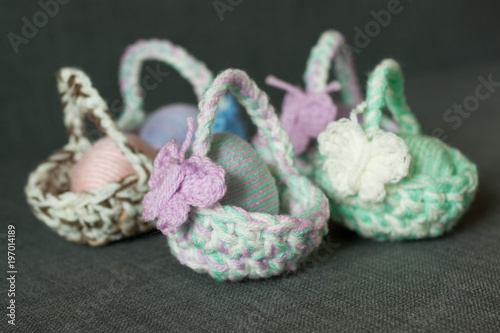 Easter decoration, crochet mini basket, striped colorful egg wrapped in soft yarn thread, pastel colors, butterfly, wooden texture background. Homemade decor. Shallow depth of focus. Easter holidays.