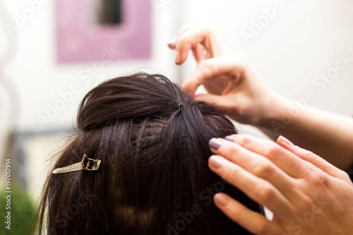 the hairdresser does a hairstyle for a young woman
