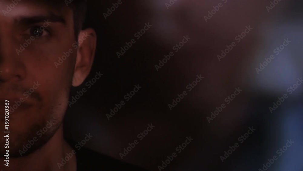 Close-up of a Male's Gray Eye watching a video or film on TV or a computer monitor. Reflection on his face Close-up of a Male's Gray Eye watching a video or film on TV or a computer monitor. Reflection on his face