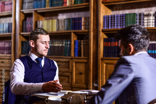 Men in suit with antique bookshelves on background.