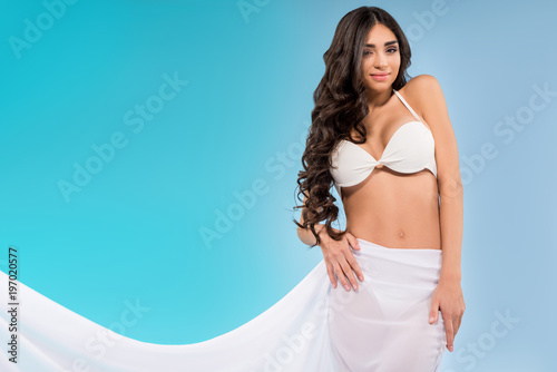 attractive woman in bikini posing with white veil, isolated on blue