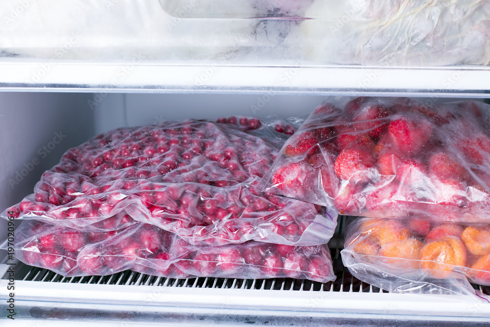 Frozen berries and fruits in bags in freezer, close up - obrazy, fototapety, plakaty 