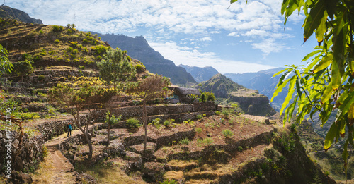 Hiker with camera among agriculture terraces nestled into the slopes of gorgeous mountains. Trekkingtrail Corda Coculli Santo Antao Cape Verde photo