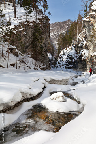 Winter landscape with a fast mountain river. Tourists travel through the gorge of a stream