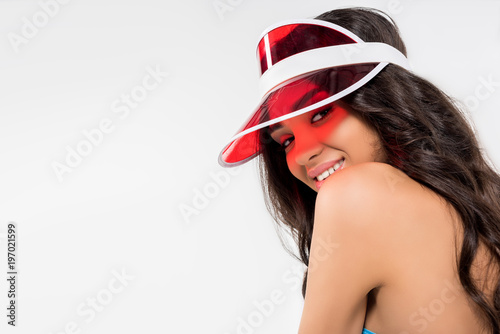 attractive tanned girl posing in red visor, isolated on white
