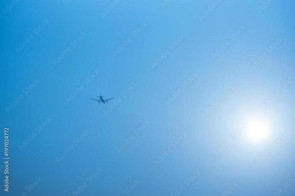 Airplane flying in the blue sky among clouds and sunlight Airplane flying in the blue sky among clouds and sunlight