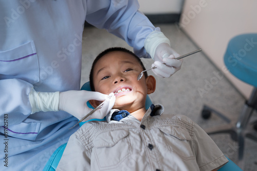 Hands of dentist holding a dental tool. Checking the teeth to the boy lying in the dental chair in a hospital.