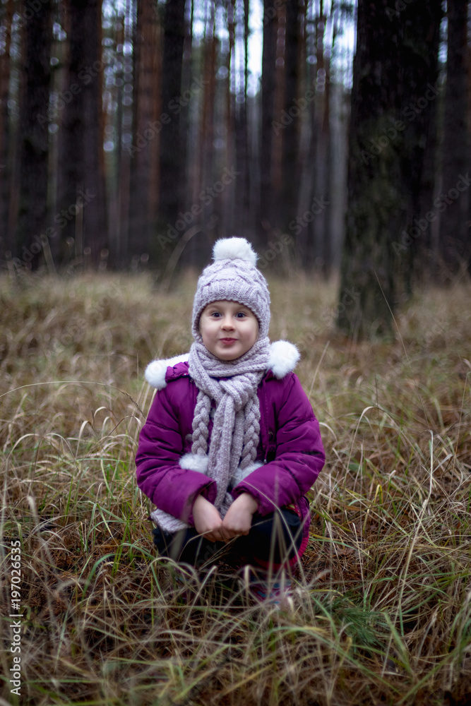 Cute little girl posing in autumn forest on the dry grass Cute little girl posing in autumn forest on the dry grass