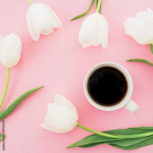 White tulips flowers with mug of coffee on pink background. Blogger composition. Flat lay, top view.