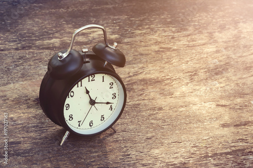  Black Alarm Clock vintage on wooden table and abstract nature background 