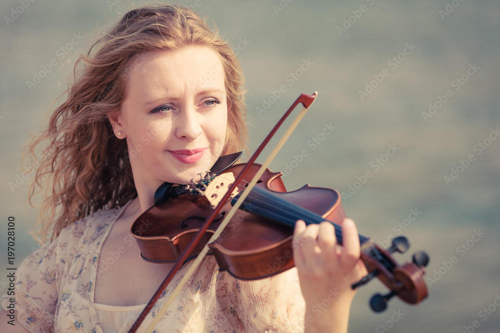 Woman playing violin on violin near beach