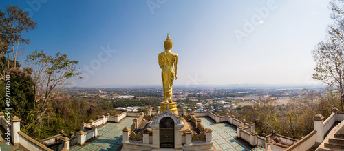 Panorama view of gold buddha monk statue on the mountain with city background photo