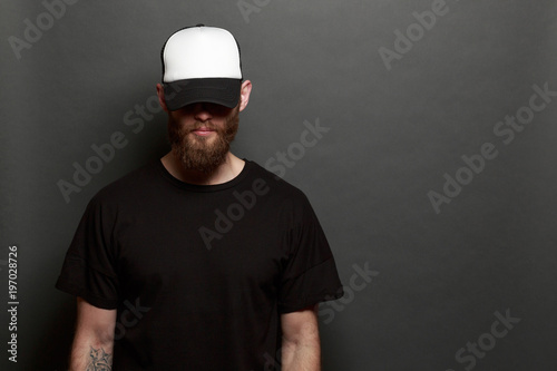 Photography Hipster man walking wearing black jeans, t-shirt and a white baseball cap