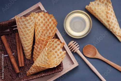 Empty waffle cones Homemade Dessert with wooden Accesories and honney. Blue Background. Top view photo