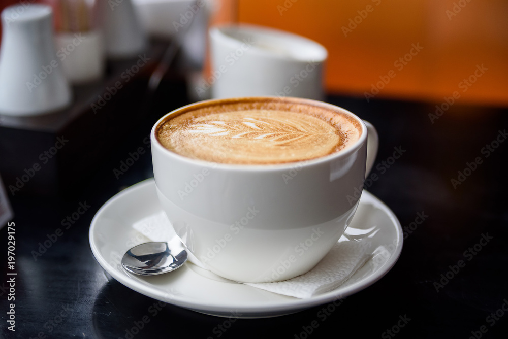 Fototapeta premium Cappuccino in a white cup on restaurant table