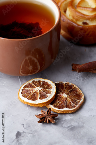 Homemade rose bread, cup of tea, dried citrus and spicies on white textured background, close-up, shallow depth of field