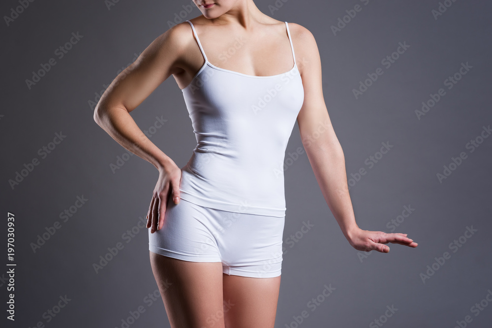Fototapeta premium Slim woman in white underwear on gray studio background, perfect female body