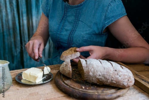 Woman puts butter on rye bread breakfast concept