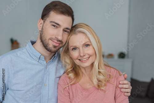 portrait of grown son hugging smiling mother and looking at camera