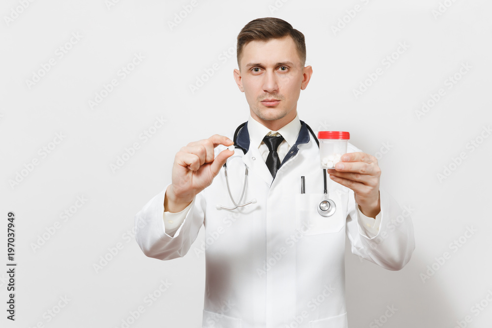 Serious experienced handsome young doctor man isolated on white background. Male doctor in medical uniform, stethoscope holding bottle with white pills. Healthcare personnel, health, medicine concept. Serious experienced handsome young doctor man isolated on white background. Male doctor in medical uniform, stethoscope holding bottle with white pills. Healthcare personnel, health, medicine concept.