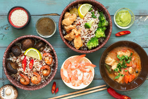 Rice with prawns, chicken, mushrooms, broccoli on a naked rustic background. Asian dishes. Concept of Asian food. View from above.