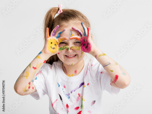 Little girl covered in paint making funny faces.
