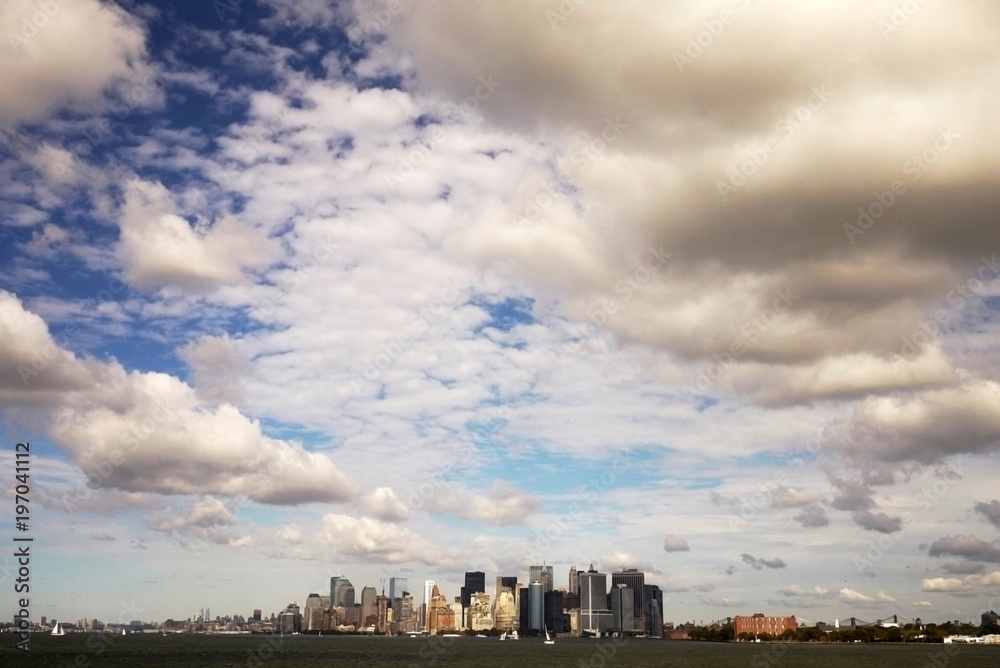Manhattan under the cloudy sky with the long distance view from ferry in New York