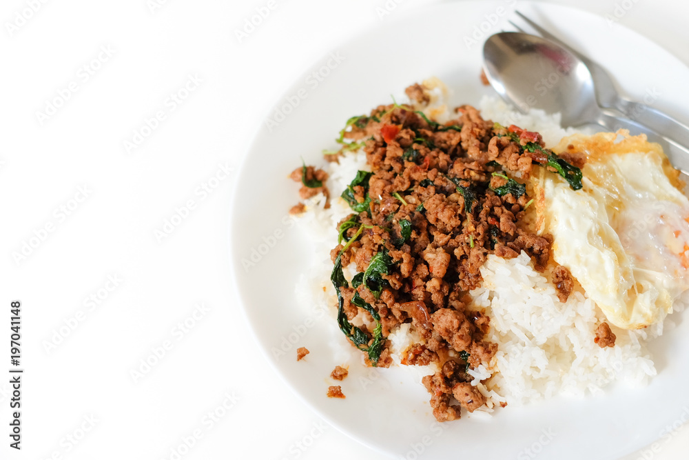 Rice topped with stir-fried pork and basil serve with fried egg on white plate & spoon, fork set on the table - Thailand food popular & nice to eat concept. Rice topped with stir-fried pork and basil serve with fried egg on white plate & spoon, fork set on the table - Thailand food popular & nice to eat concept.